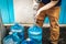 Man in work pants with metal nozzle filling blue bottles with water to use in cabin with no running water - standing beside