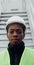 A man in work uniform smiles looking at the camera standing near a wind turbine