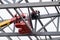 Man worker on a crane performs high-rise work on welding metal structures of new tower at height