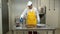 Man worker disinfects sausage making machine parts in industrial workshop.