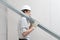 Man worker with drywall metal profiles for installing plasterboard sheet to wall. Wearing white hardhat, work gloves and safety