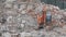 Man worker on excavator works on construction garbage dump.