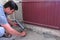 Man worker fills crack between wall and cement floor with mounting foam in room.