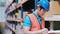 Man worker holds clip charts and takes notes in the automotive parts warehouse distribution store.  Engineers wear a safety helmet