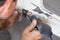 Man worker with Industrial soldering gun of black color on the floor among dust and tools for heating and melting plastic during