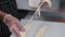 A man worker rips soft cheese into long pieces