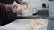 A man worker rips soft cheese into pieces