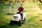 Man worker using ride on lawnmower, male riding lawn tractor and relaxing during sunset golden hour