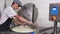 A man working at cheese production factory - mixing the small pieces of soft cheese in the vat using an iron plate