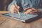 Man working contemporary electronic tablet while sitting at the wooden table at office.Men using digital stylus for