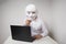 A man working at a laptop, covers his face with a mask, the concept of anonymity on the Internet