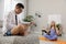 Man working on laptop while his wife practicing yoga in room. Stay at home concept