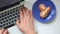 A man is working with a laptop. Type the text on the keyboard. From time to time, eating a mandarin lying on a saucer. View from a