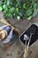 Man working in vegetable garden with bamboo sticks for tie the plants near wheelbarrow full of fertilizer and gardening equipment