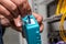 A man works with a blue fiber optical connector cleaner near a cabinet. Cleaning connectors close up. Horizontal