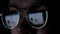 Man works on internet with the reflection of a monitor inside glasses. Concept. Close up of male face wearing glasses