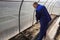 A man works in a vegetable garden in early spring. Digs the ground. Working in a greenhouse