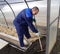 A man works in a vegetable garden in early spring. Digs the ground. Working in a greenhouse