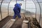 A man works in a vegetable garden in early spring. Digs the ground. Working in a greenhouse