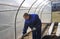 A man works in a vegetable garden in early spring. Digs the ground. Working in a greenhouse