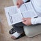 Man with a wrapped foot sitting on sofa reading work injury claim form