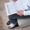 Man with a wrapped foot sitting on sofa reading work insurance claim form