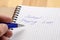 A man writes a blue pen in his notebook. Sign - school shopping list. Close-up