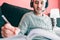 Man writing in his work schedule, wearing headphones.