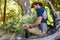 Man writing on notepad while resting on tree trunk