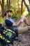 Man writing on notepad while resting on tree trunk