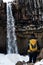 A Man with yellow backpack standing alone at Svartifoss waterfall in Iceland. Travel lifestyle concept