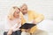 A man in a yellow cardigan and a woman in a pink sweater are sitting and reading documents in a black folder.