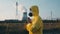 Man in yellow chemical protection suit and face protective mask Praying against the backdrop of a nuclear power plant