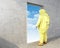 Man in yellow chemical protective suit looks in the opening in the wall with the sky