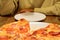 Man in yellow clothes at table in front of large dish with freshly baked pizza