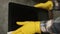 A man in yellow gloves wipes the laptop screen