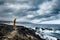 Man with yellow jacket in a wild place on the ocean coast looking the power of the waves in a bad weather. challenge and enjoying