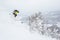 Man in yellow jumps off a cornice near the summit of a small peak in the backcountry of Hokkaido, Japan