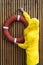 Man in a yellow raincoat hangs a red lifebuoy on a slatted wooden wall in the rain weather, back view. Outdoors