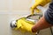 Man in yellow  rubber gloves holds a spray cleaner bottle and wipes handheld shower head with hose