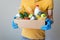 Man in yellow t shirt and gloves holds box of food. Donation box with food supply, canned food, cereals, vegetables