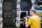 A man in a yellow T-shirt is near the main router. System administrator with a laptop sitting in the server room. Programmer