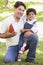 Man and young boy outdoors with football smiling