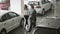 The manager of car showroom demonstrates the automobiles to young couple