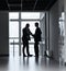 Manager and employee discussing documents in office corridor