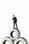 Manager figurine standing on cogwheels against white background