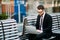 Manager with a laptop sitting on bench in a modern city outdoors