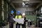 Manager supervisor, engineer and industrial worker in uniform discussing blueprints in large metal factory hall.