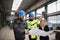 Manager supervisor, engineer and industrial worker in uniform discussing blueprints in large metal factory hall.