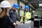 Manager supervisors and industrial worker in uniform doing control in large metal factory hall and talking.